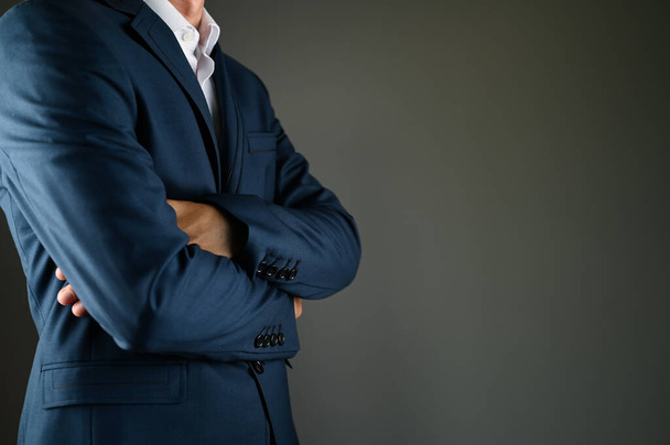 L'uomo in giacca e cravatta incrocia le braccia. Un uomo in giacca e cravatta su sfondo nero. Concetto: costruzione in azienda - Foto, immagini