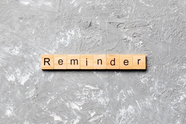 Слово REMINDER, написане на дерев'яному блоці. Текст на цементному столі для вашого бажання, концепція
. - Фото, зображення