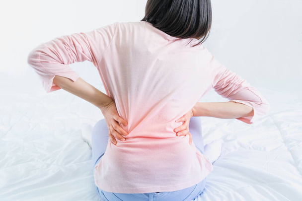 Attractive woman with back pain at home in the bedroom,This bed is not comfortable as I thought,female with waist pain - Foto, Imagem