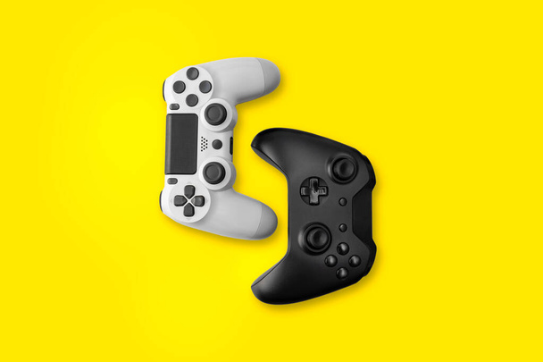 黄色の背景に白と黒のゲームコントローラー - 写真・画像