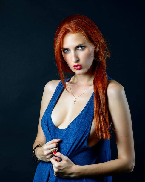 Retrato de arte de moda de bela menina modelo de moda de cabelos vermelhos com cabelos longos em vestido azul sobre fundo escuro, em iluminação colorida. - Foto, Imagem