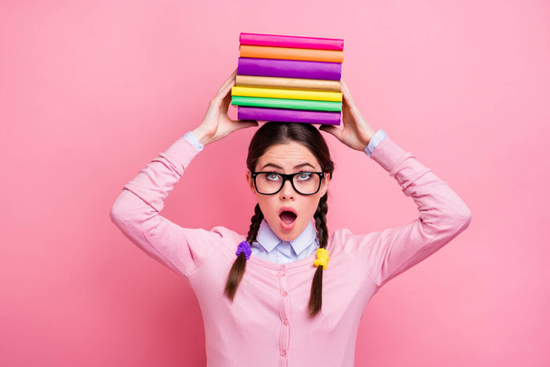 Close-up portrait of her she nice attractive pretty lovely funny girlish overwhelmed brown-haired teenage girl holding pile book on head hard course isolated over pink pastel color background - Photo, Image