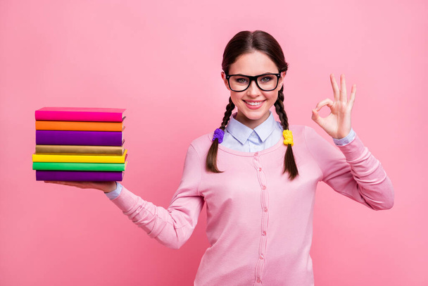 Photo of pretty student lady hold literature pile diligent pupil prefer reading not watching tv approve interesting story read books wear shirt pullover specs isolated pink color background - Фото, зображення
