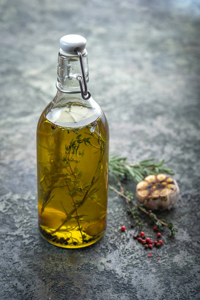 Olivenöl in einer Flasche mit Rosmarin und Thymian im Inneren, würzig aromatisches Speiseöl - Foto, Bild
