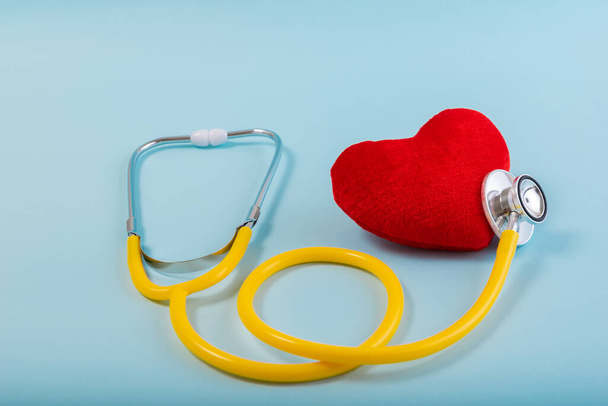 Red heart, Yellow Stethoscope on blue background with Copy space. Medical concept, Health care concept. - Photo, Image