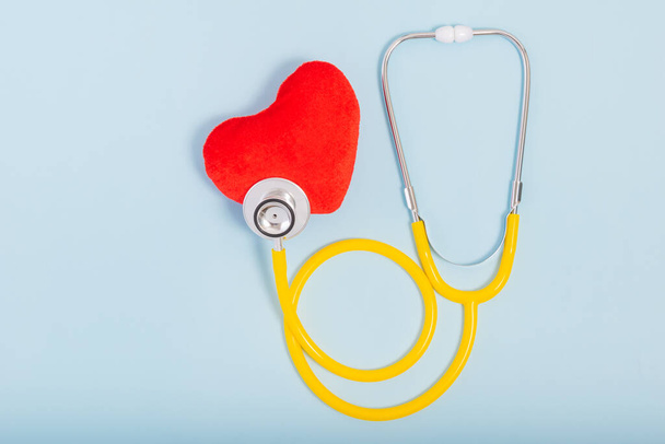 Corazón rojo, Estetoscopio amarillo sobre fondo azul con espacio de copia. Concepto médico, concepto de salud. - Foto, Imagen