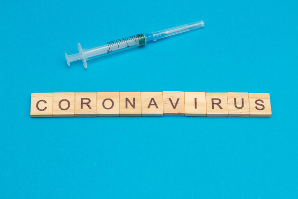 Word CORONAVIRUS made from wooden cubes on blue background - Photo, Image