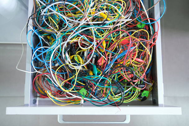 Zdezorganizowane kolorowe kable na szufladzie. Niechlujne druty. - Zdjęcie, obraz
