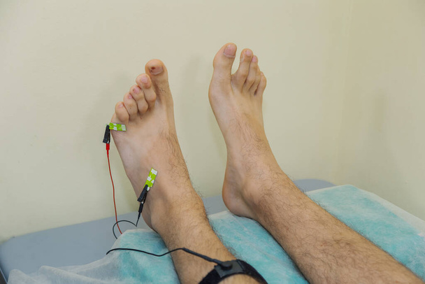Un uomo con dei sensori sulla gamba in clinica. - Foto, immagini