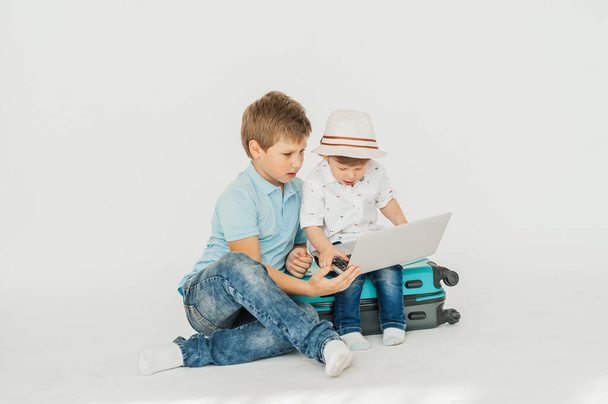 Two Happy boys, brother and brother are carrying a big suitcase on a white background, and expecting the big vacation - Foto, Imagen