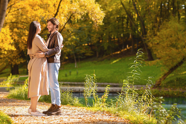 Romantický pár objímající jeden druhého, stojící vedle řeky - Fotografie, Obrázek
