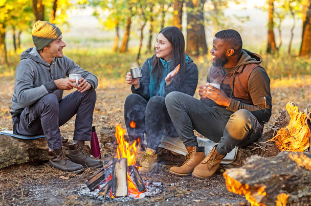 Grupo de amigos cerrados disfrutando del té caliente en el campamento - Foto, imagen