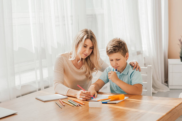 smiling mother helping adorable son doing schoolwork at home - Zdjęcie, obraz