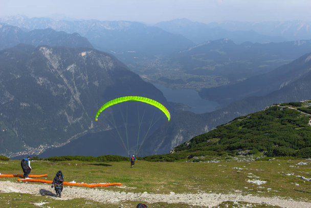 A paraglider at the start of the Krippenstein mountain in the Dachstein area,Austria.Paraglide silhouette over Hallstatter See.Extreme adrenaline sport.Wild free atmosphere.Person in the air. - Photo, Image