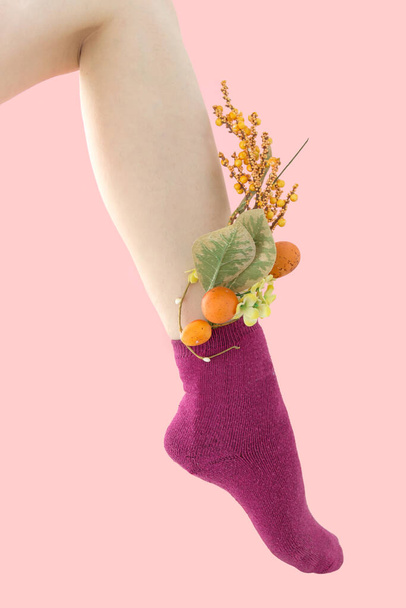 Jambe non rasée en chaussettes rose foncé. Les fleurs jaunes sont dans les chaussettes. fond rose. - Photo, image