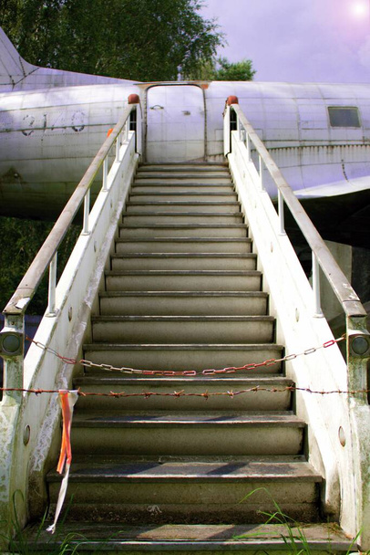 Brak wejścia na schody uziemionego samolotu.Uziemiony samolot popada w ruinę, a jego schody porośnięte są trawą.. - Zdjęcie, obraz