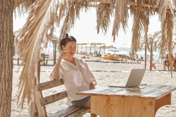 Jeune femme utilisant un ordinateur portable sur une plage. Concept de travail indépendant - Photo, image