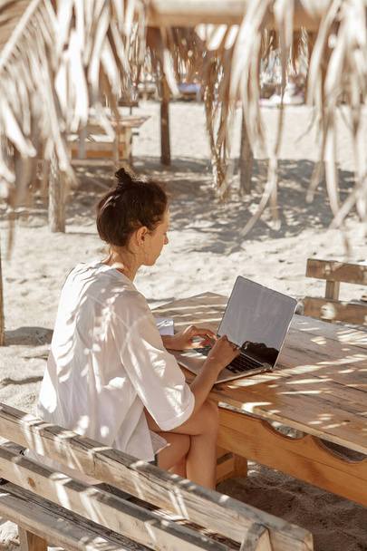 Młoda kobieta używająca laptopa na plaży. Koncepcja pracy na własny rachunek - Zdjęcie, obraz
