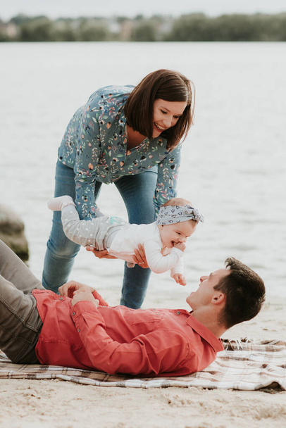 famille heureuse reposant au bord du lac. famille avec un petit enfant. - Photo, image