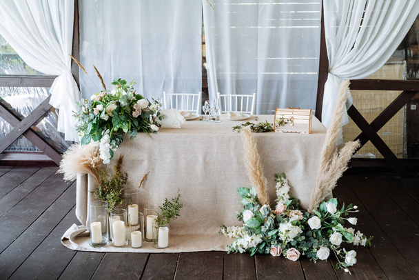 virágok és gyertyák az esküvői asztal díszítésében, esküvői dekoráció, természetes anyagokból készült asztalterítő, asztalterítő. - Fotó, kép