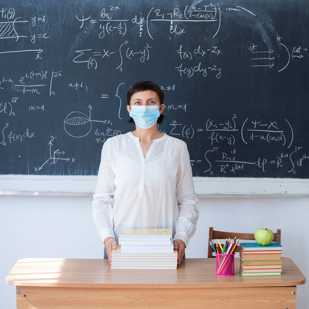 Teacher with face mask welcoming children back at school after lockdown. Back to school during COVID-19 pandemic. - Photo, image
