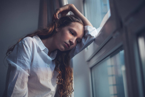 Sad teen near window - Фото, изображение