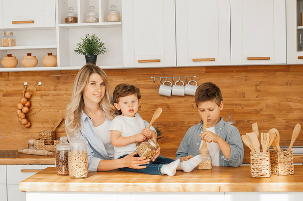 Mom with her 2 years old child cooking holiday pie in the kitchen to Mothers day, casual lifestyle photo series in real life interior - Foto, Bild