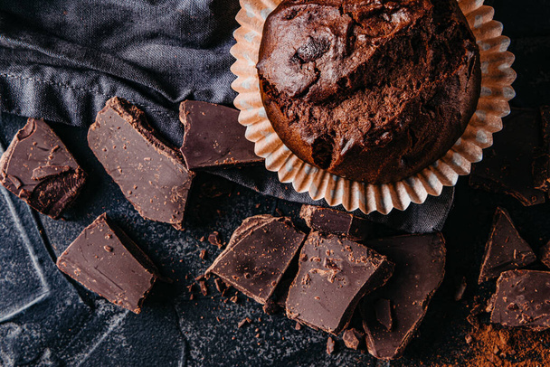  Çikolatalı kek ve siyah arka planda çikolata parçaları. - Fotoğraf, Görsel