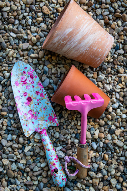 coloridas herramientas de jardín con macetas de barro de terracota sobre un fondo de grava - Foto, Imagen