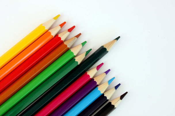 Colored pencils on a white background. Lots of different colored pencils. Colored pencil. Pencils are sharp. Pencils lie diagonally in the lower left corner.Close-up. Copy space. Background. Flat lay - Photo, Image