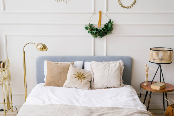 Decoración de Navidad en el dormitorio. Cama con almohadas, corona sobre la cama - Foto, imagen