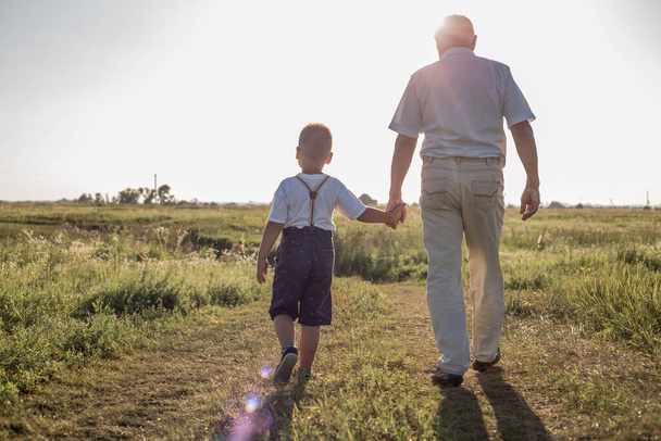 Boldog gyerek nagyapával a mezőn. Nyugdíjas nagyapa. Nyugdíjas anyavállalat - Fotó, kép