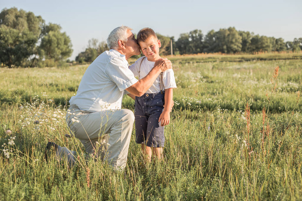 Happy child with Grandfather playing at the meadow. Grandpa retiree. Retirement parent - Photo, Image