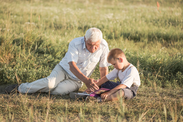 Grand-père et son petit-fils lisant le livre en plein air - Photo, image