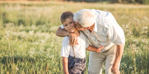 concept de famille, de génération, de communication et de personnes - heureux grand-père embrasse son petit-fils à la prairie d'été - Photo, image