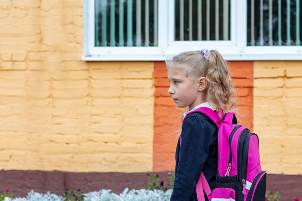 Fényes nappal. egy fiatal lány, öreg hajjal és hátizsákkal a vállán iskolába jár. - Fotó, kép