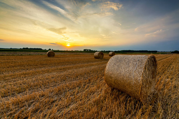 Прекрасный летний восход солнца над полями с тюками сена - Фото, изображение