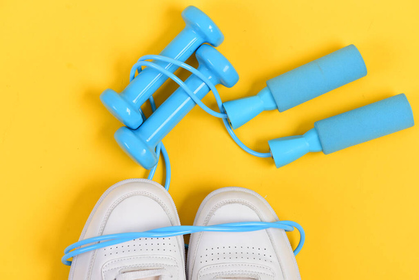 Sneakers with skipping rope on yellow background. - Foto, immagini