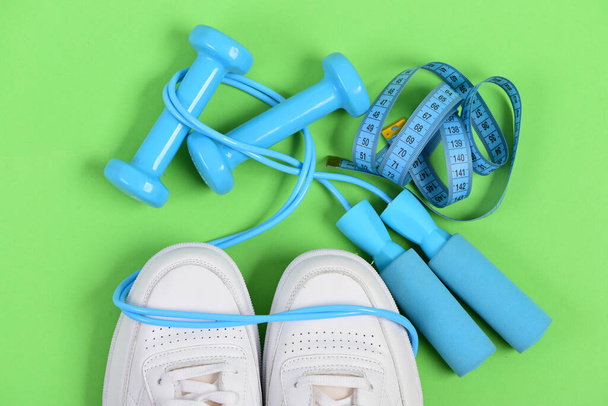 Sneakers with skipping rope and tape on green background. - 写真・画像
