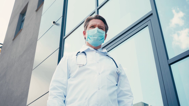 alacsony szög kilátás orvos orvosi maszk áll klinika közelében kívül - Felvétel, videó