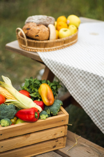 A box with a harvest of vegetables is on the street. Peppers, corn, broccoli, tomatoes and herbs inside the box. Autumn harvest. - Foto, imagen