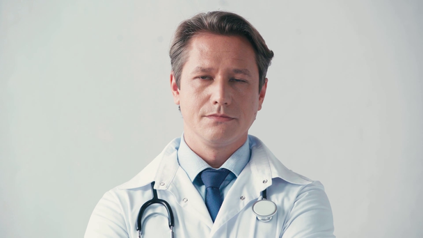 με αυτοπεποίθηση γιατρός σε λευκό παλτό κοιτάζοντας κάμερα απομονωμένη σε γκρι - Πλάνα, βίντεο