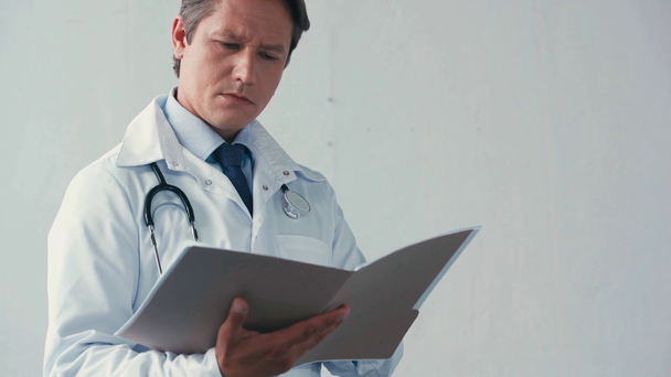 súlyos orvos fehér köpenyben nézi mappa szürke - Felvétel, videó