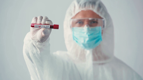 focus pull of scientist in hazmat suit holding test tube on grey - Footage, Video