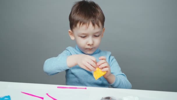 Beelden van vier jaar oud kind beeldhouwen in plasticine op grijze achtergrond - Video