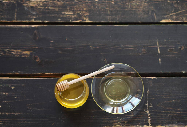 There is honey and a spoon with honey on a dark wooden background on a kitchen board. The idea of natural products. - Φωτογραφία, εικόνα
