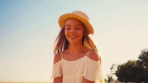 menina alegre em vestido branco e chapéu de palha andando no campo de trigo  - Filmagem, Vídeo