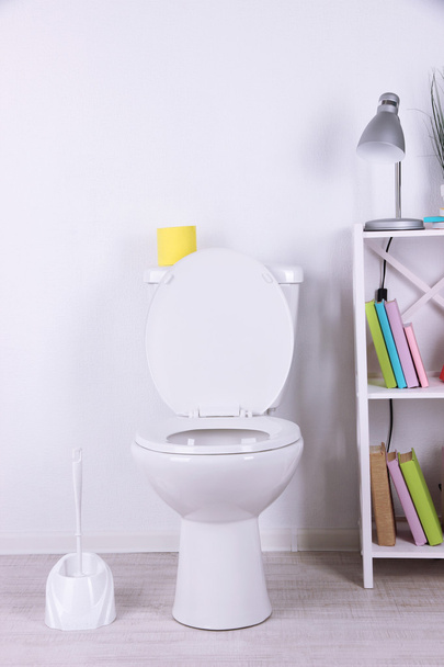 White toilet bowl and stand with books, on color wall background - Фото, изображение
