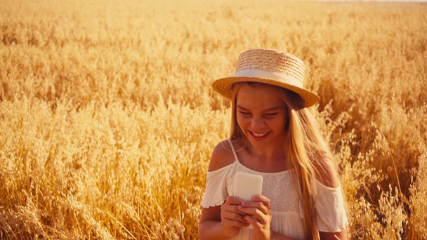 Tyttö valkoinen mekko ottaen selfie ja osoittaa rauhan merkki vehnäpellolla  - Materiaali, video