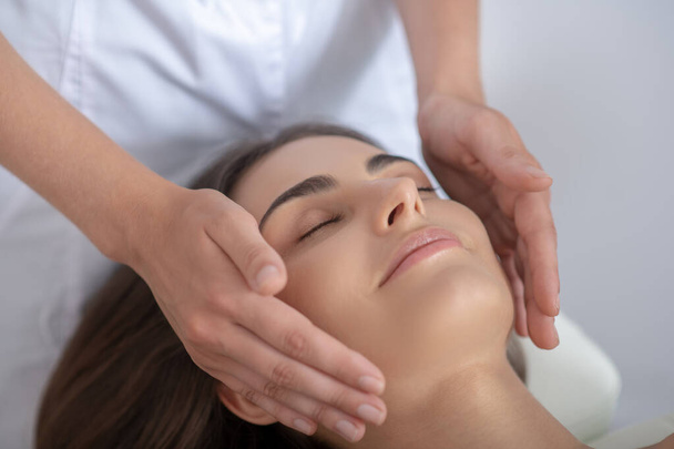 Professional massage therapist doing face massage to a woman - Photo, image